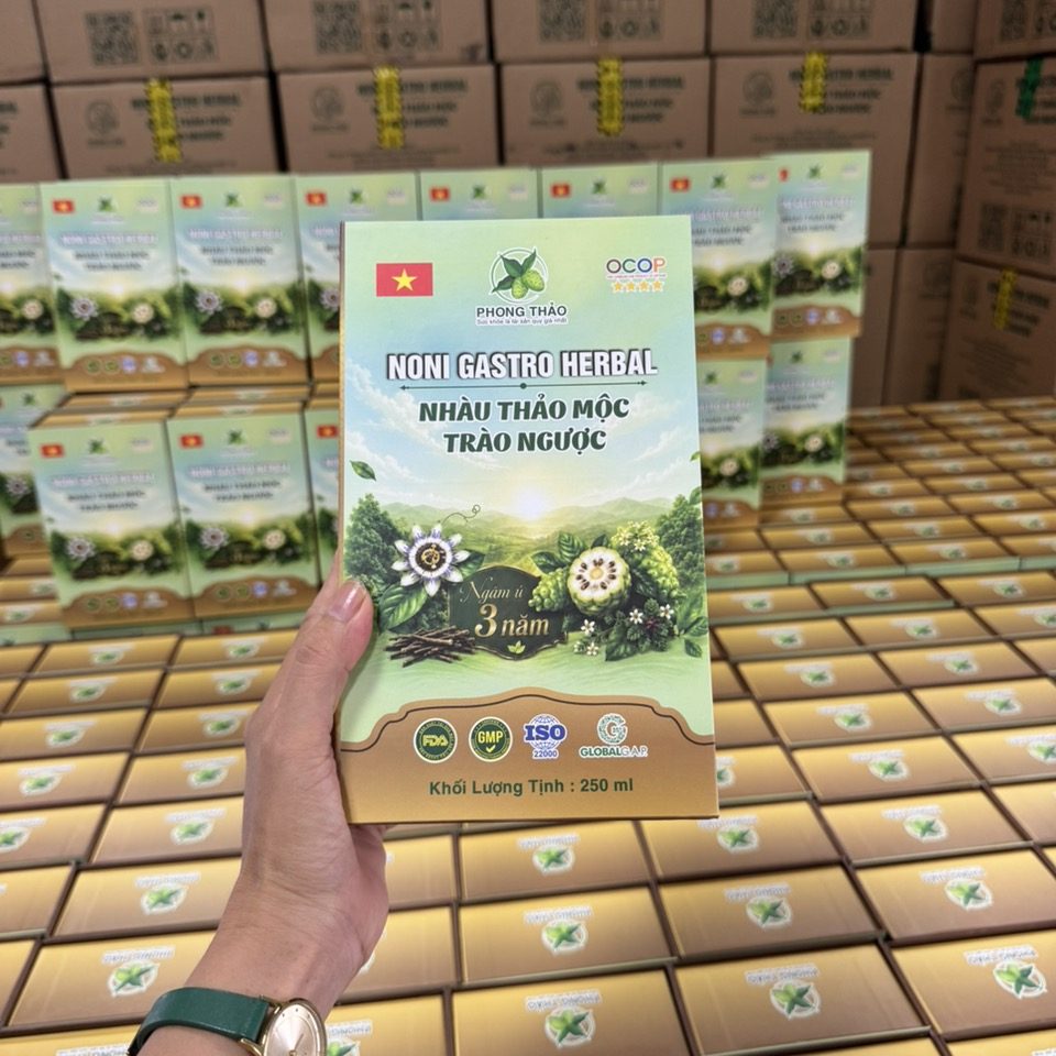 Hộp Nhàu Thảo Mộc Trào Ngược – Noni Gastro Herbal cầm trên tay, phía sau là kho hàng